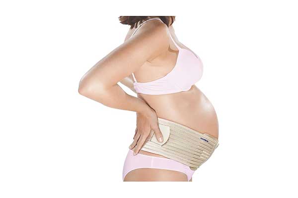 Foto com foco na barriga e no tórax de uma mulher grávida. Ela está de lado, com as mãos nas costas, usa, calcinha, sutião e uma faixa na barriga