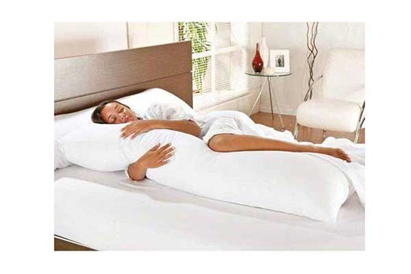 mulher deitada em uma cama agarrada a um travesseiro em formato de U