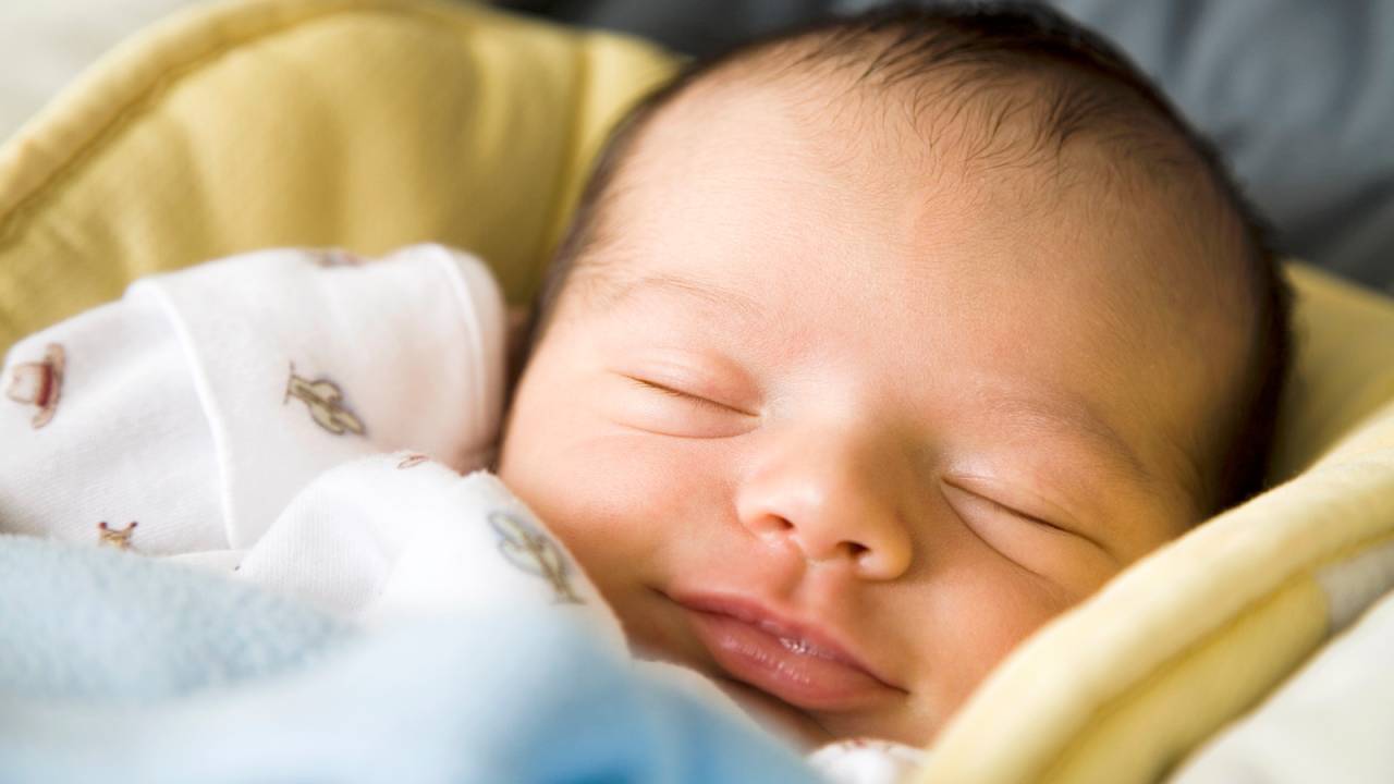 bebê recém nascido sorrindo enquanto dorme