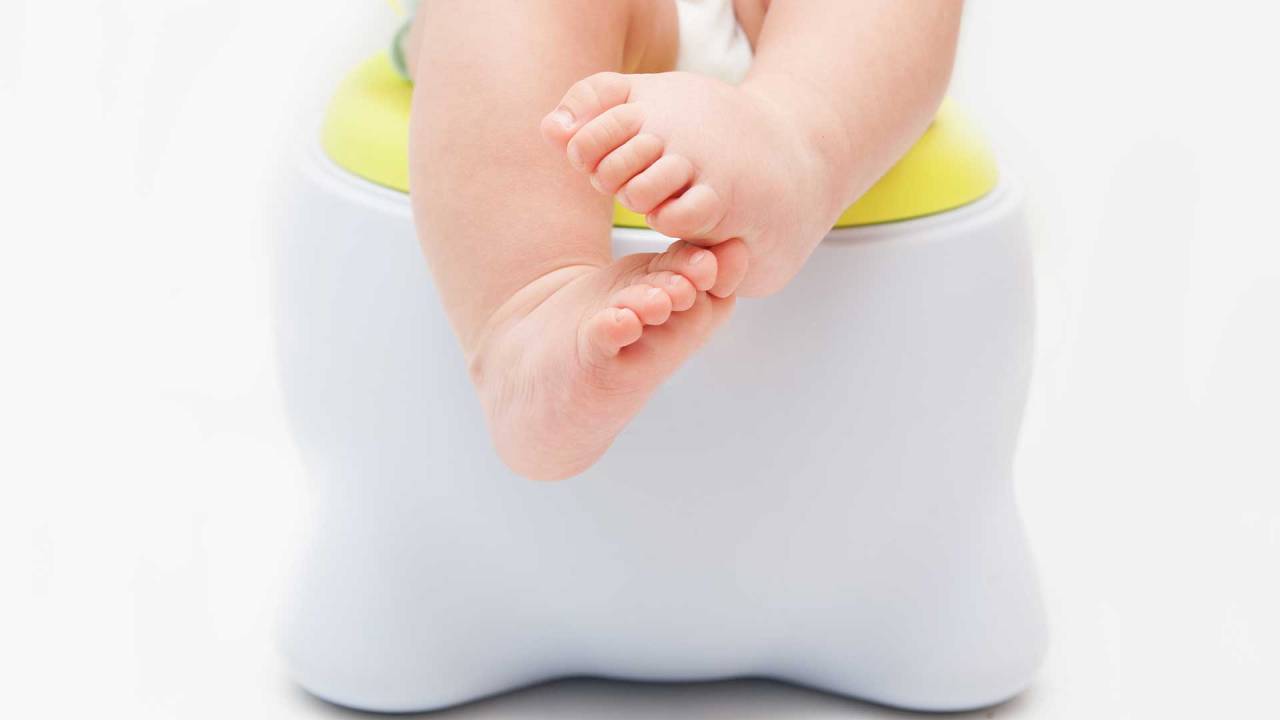 pés de um bebê que está sentado em um troninho infantil