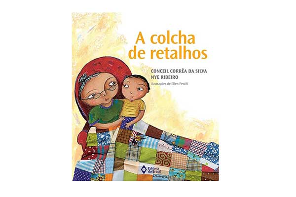 capa do livro A Colcha de Retalhos, com ilustração de uma avó sentada em uma poltrona com o neto no colo. Eles estão cobertos por uma colcha de retalhos