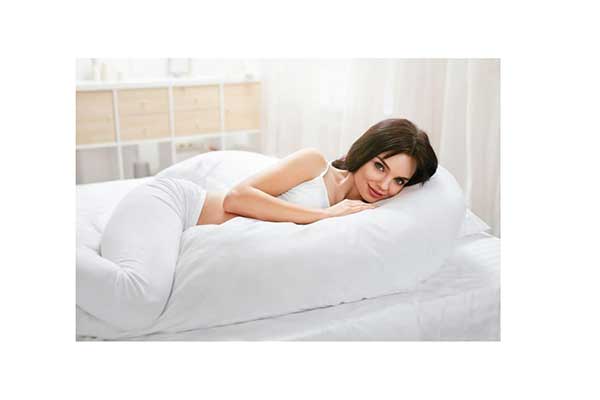 mulher deitada em um travesseiro grande e branco, em formato de U