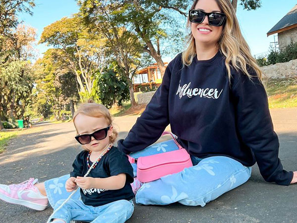 fabi-santina-entrevista-filha-gigi mulher sentada no chão com uma criança ao seu lado. Ambas usam roupas iguais e óculos esculos