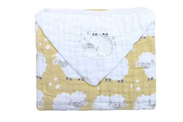 Toalha de banho infantil dobrada, com estampas de ovelhas.