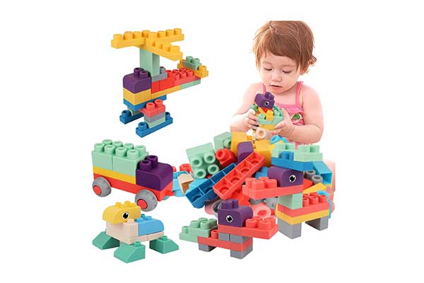 menina sentada, brincando com vários blocos de montar coloridos, alguns empilhados, alguns soltos