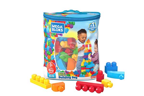 Embalagem plástica arredondada e colorida dentro da qual estão blocos de montar coloridos. Alguns desses blocos estão soltos no chão também