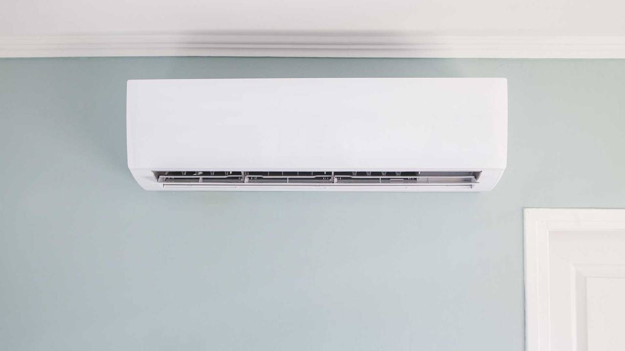 aparelho de ar condicionado branco e retangular posicionado no alto de uma parede