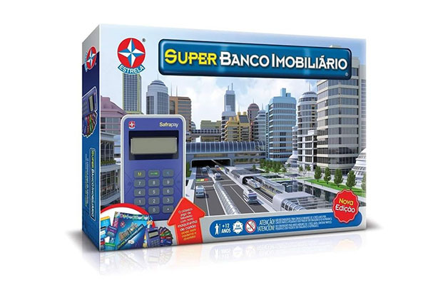 Caixa de papelão retangular, na horizontal, do jogo Jogo Super Banco Imobiliário. Ela tem a ilustração de uma cidade e de uma calculadora