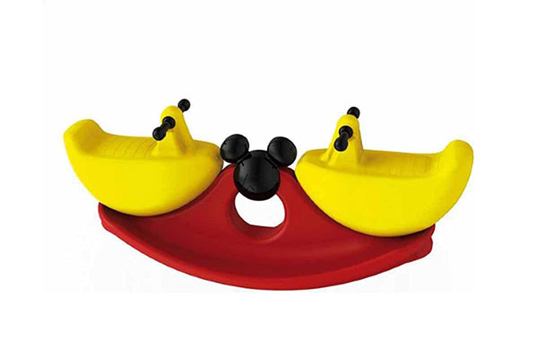 gangorra plástica de brinquedo em vermelho, amarelo e preto. No centro dela, há uma estrutura redonda com duas orelhas também redondas, remetendo à cabeça no personagem Mickey
