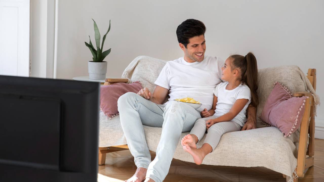 pai-filha-assistem-TV-sofa_Freepik - 2