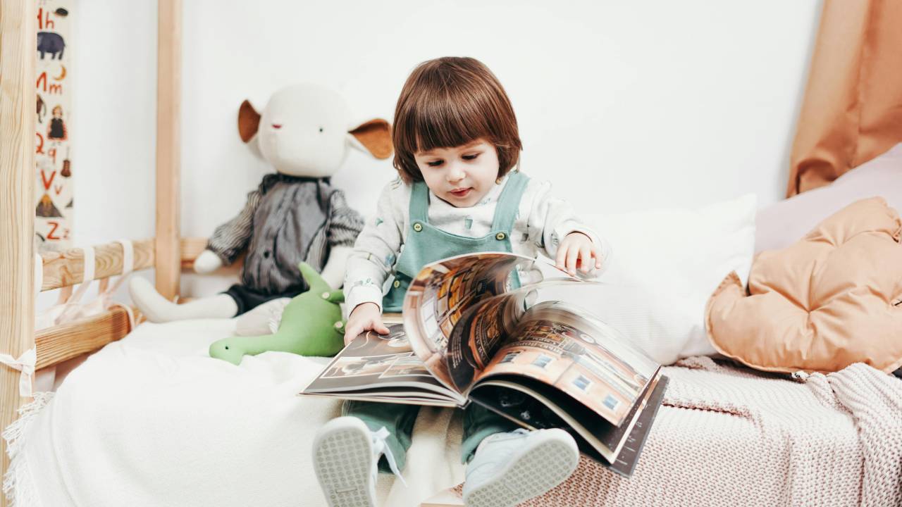 Criança brincando em / lendo livro em cama
